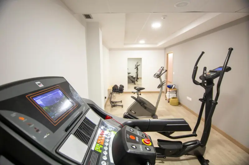Une salle de sport lumineuse avec plusieurs appareils de fitness.