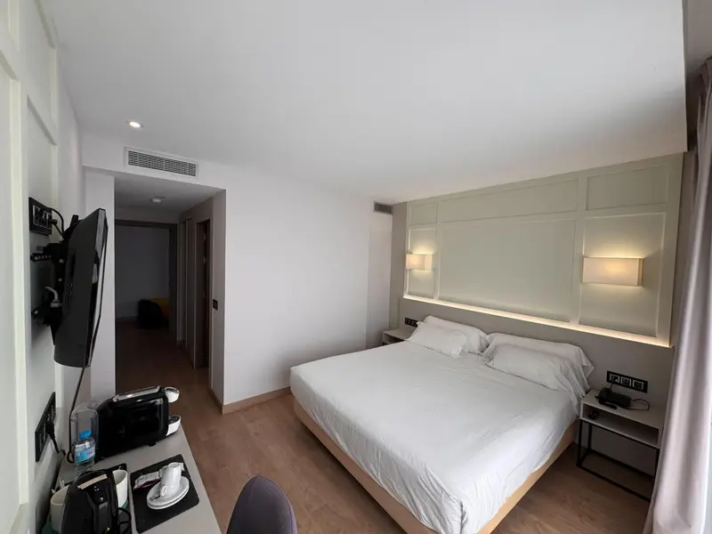 Une chambre lumineuse avec un grand lit et une télévision murale.