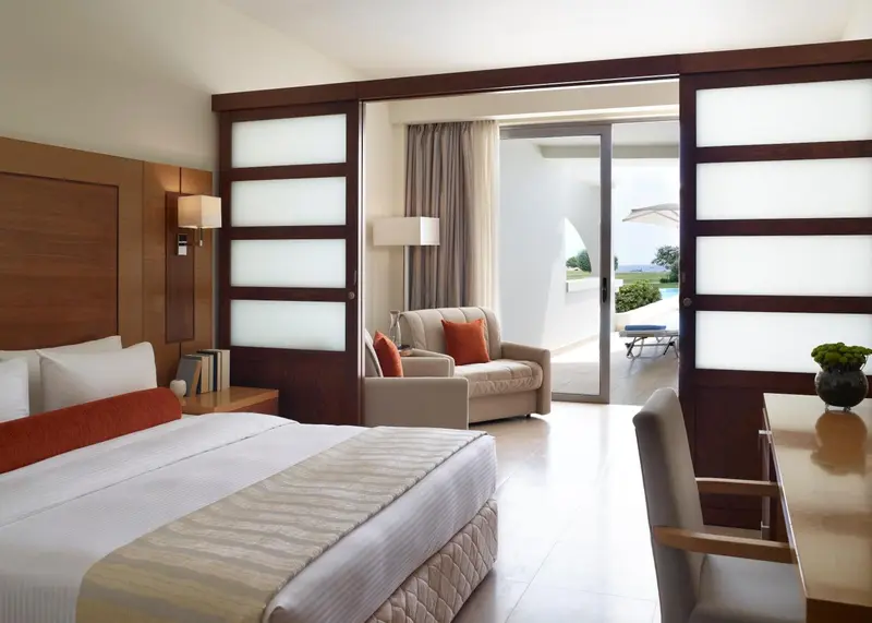 Une chambre lumineuse avec un lit et un coin salon donnant sur une terrasse.