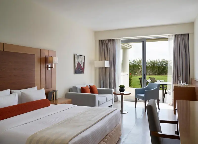 Une chambre lumineuse avec un lit, un canapé et un accès à une terrasse.