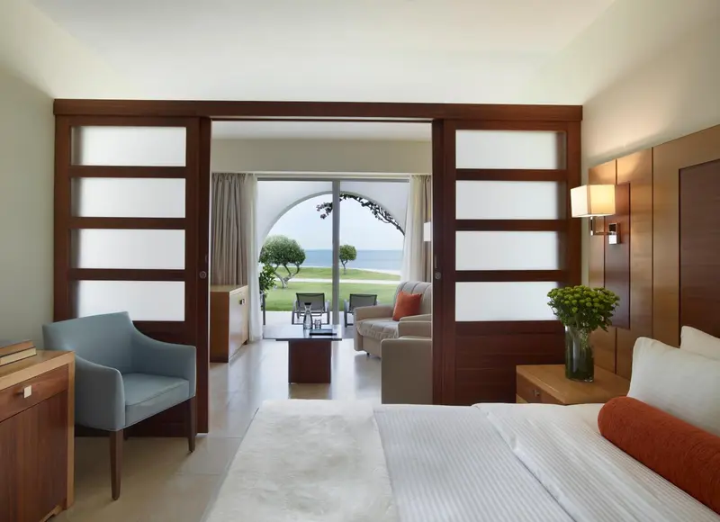 Une chambre lumineuse s'ouvre sur un salon avec vue sur un jardin verdoyant.