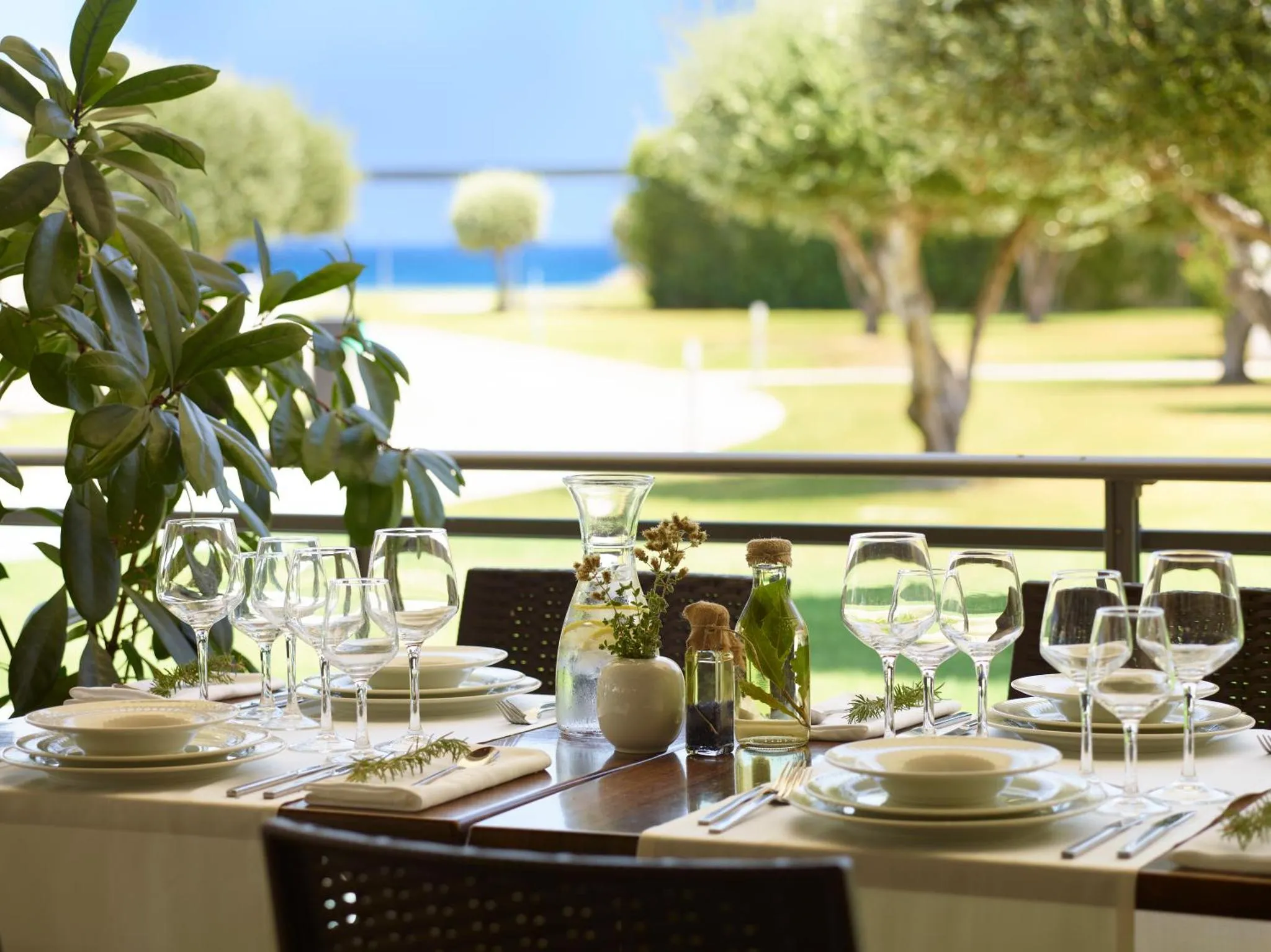 Une table dressée avec de la vaisselle et des fleurs sur une terrasse ensoleillée.