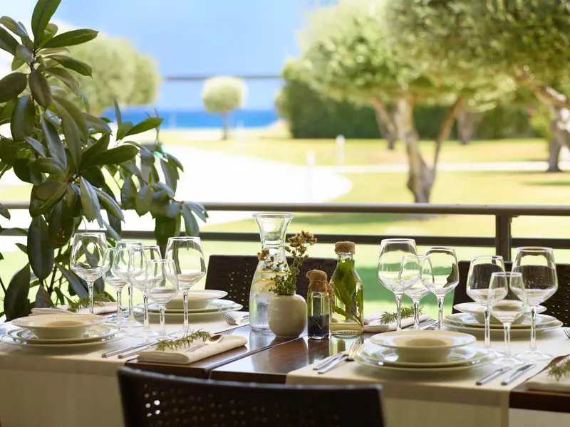Une table dressée avec de la vaisselle et des fleurs sur une terrasse ensoleillée.