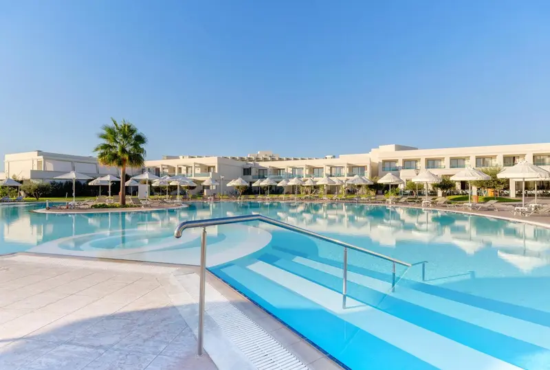 Une grande piscine rectangulaire avec des marches et des transats.
