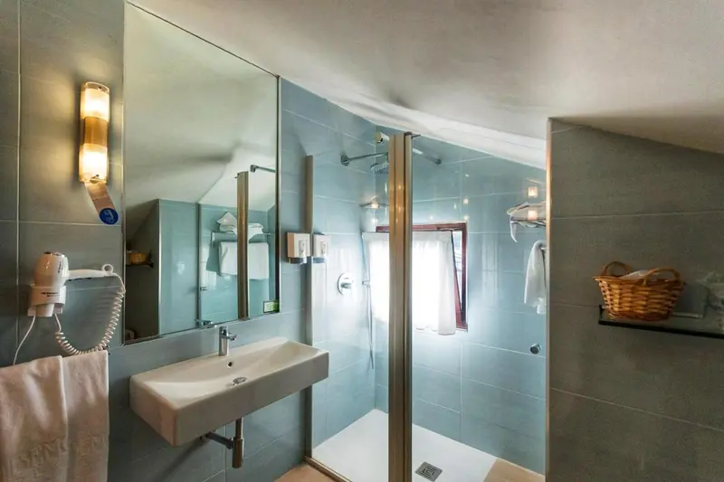 Une salle de bain claire avec une douche vitrée et un lavabo.
