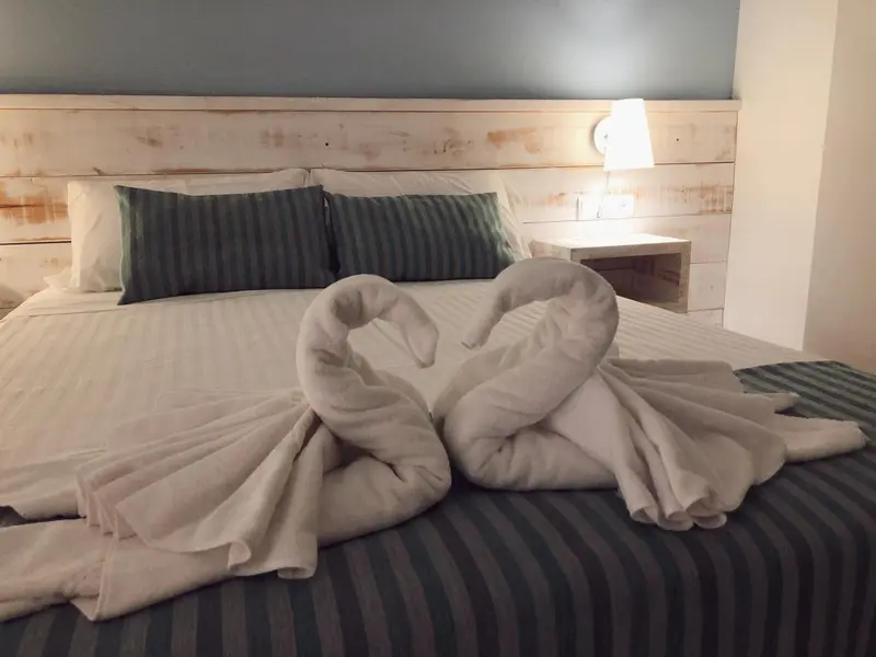 Un lit double est soigneusement fait avec des serviettes en forme de cœur.