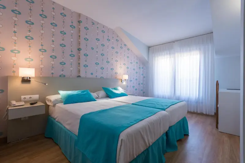 Une chambre lumineuse avec un lit double et un mur décoré de motifs.