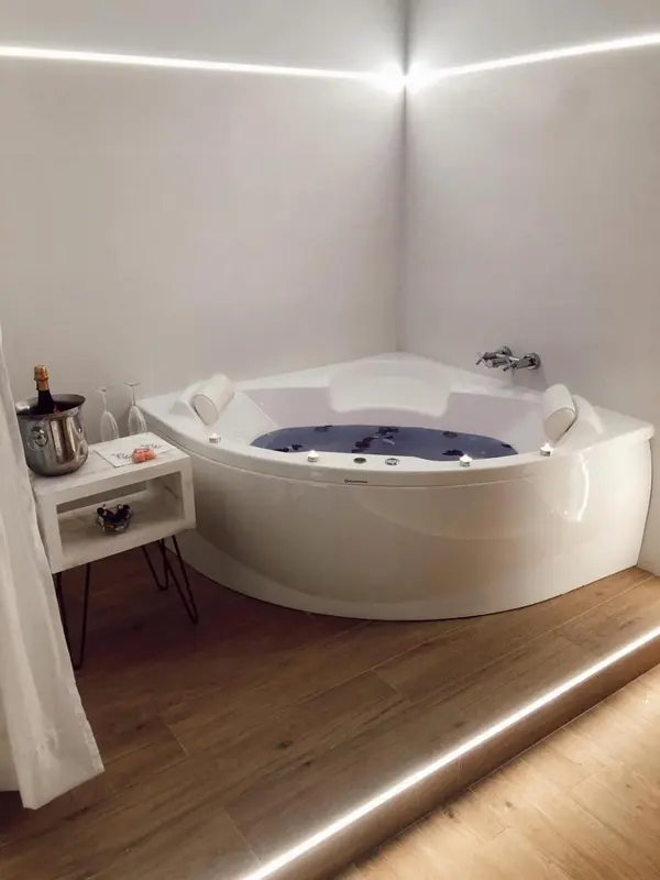 Un jacuzzi d'angle blanc est installé dans une salle de bain lumineuse.