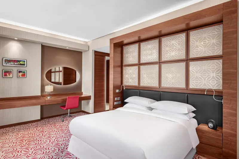 Une chambre d'hôtel moderne avec un lit blanc et un bureau en bois.