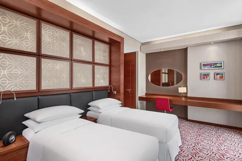 Chambre moderne avec deux lits simples et décoration murale.