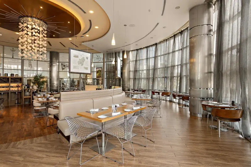 Une salle de restaurant lumineuse avec des tables dressées et de larges baies vitrées.