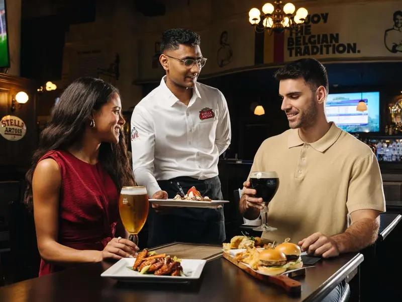Un serveur présente des plats à deux clients dans un bar.