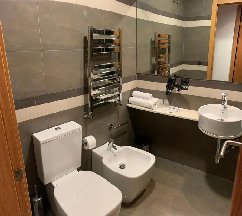 Une salle de bain moderne avec des carreaux gris et blancs, un lavabo et des toilettes.