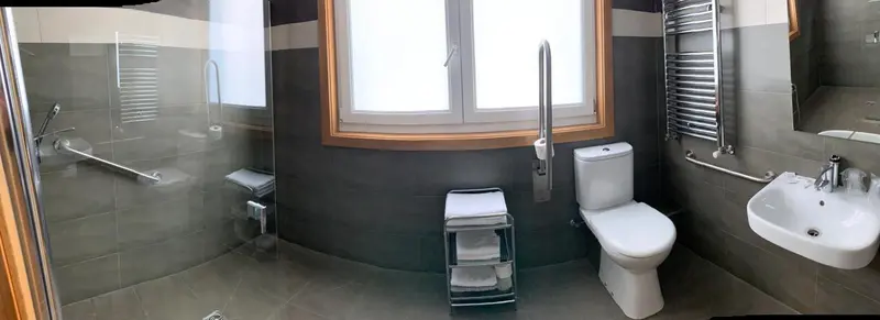 Une salle de bain moderne avec douche à l'italienne et équipements accessibles.