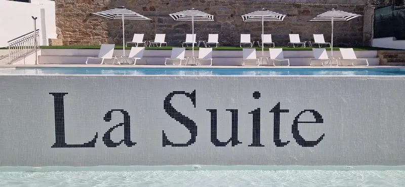 Transats blancs alignés au bord d'une piscine rectangulaire.