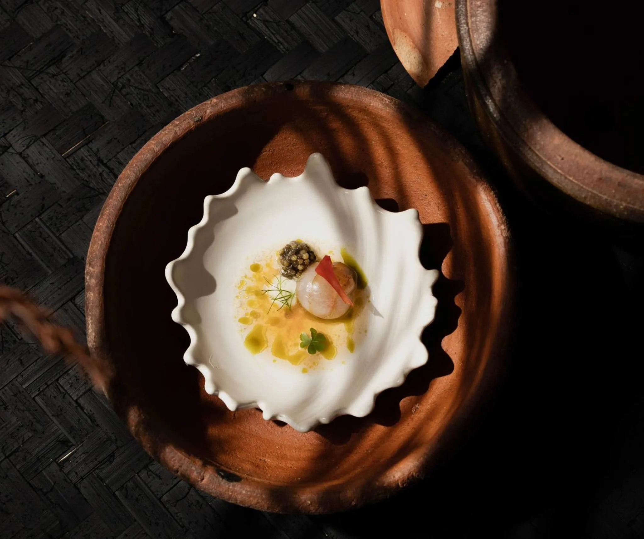 Présentation culinaire raffinée dans une assiette en forme de coquillage.