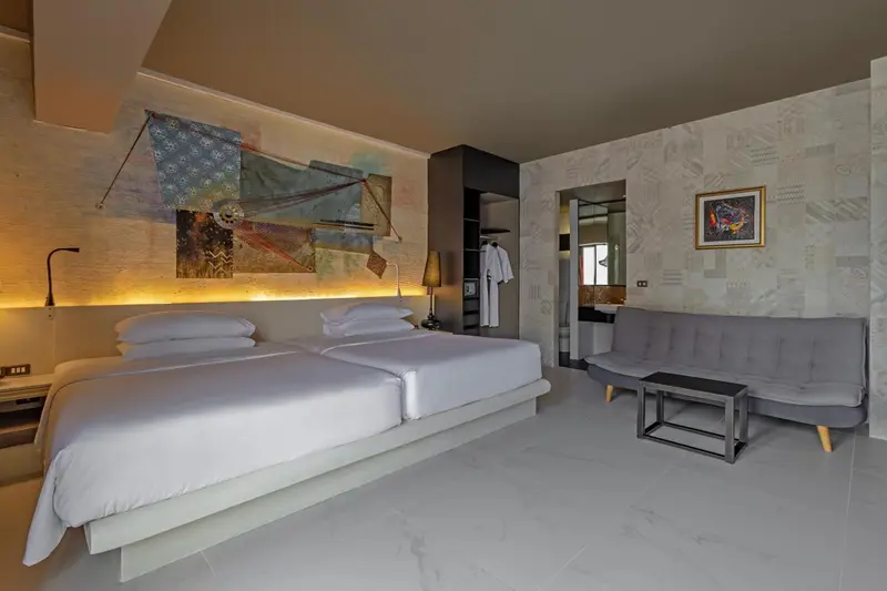 Une chambre lumineuse avec un grand lit et un coin salon.