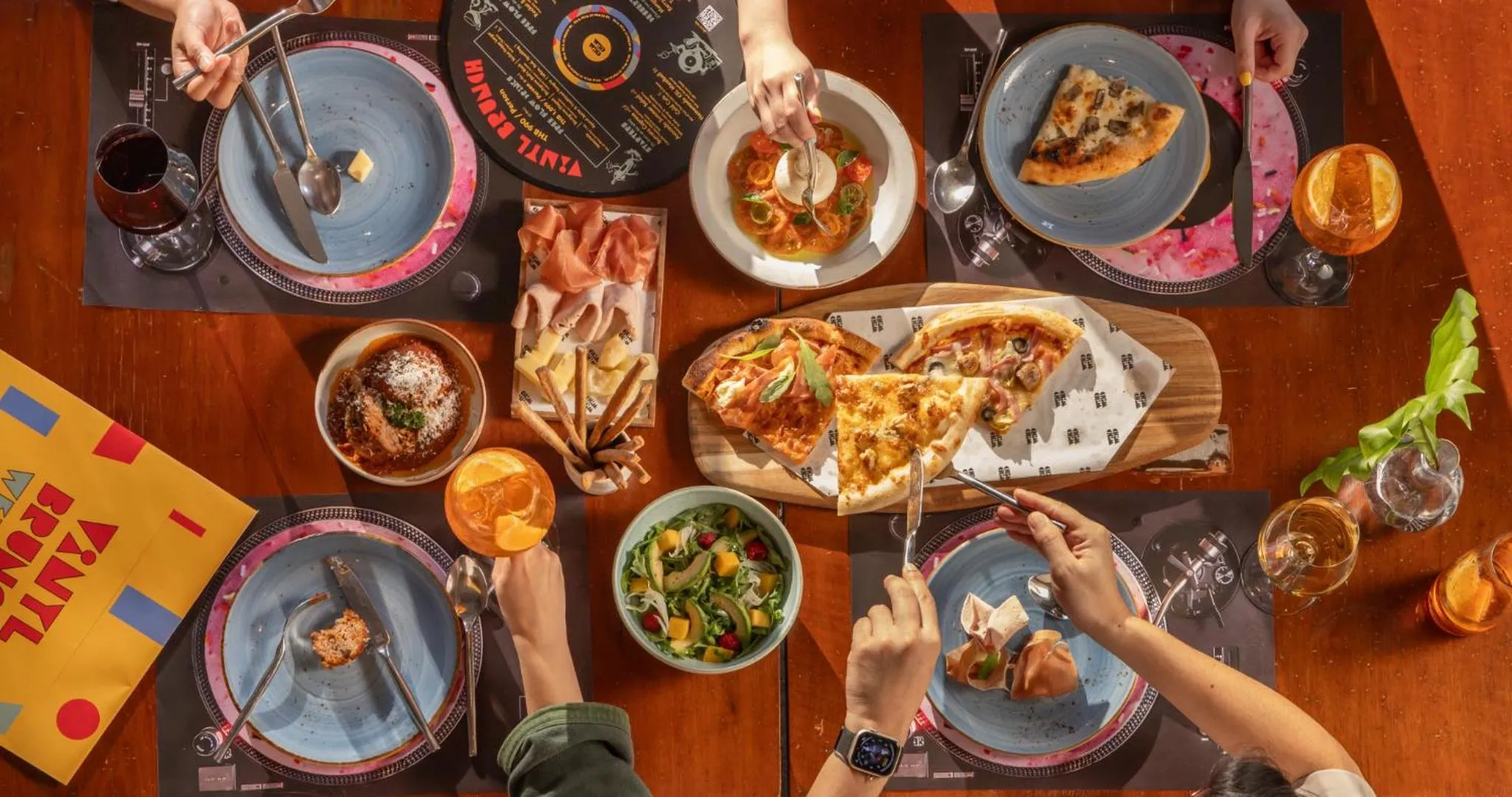 Une table vue d'en haut présente divers plats et boissons servis à plusieurs convives.