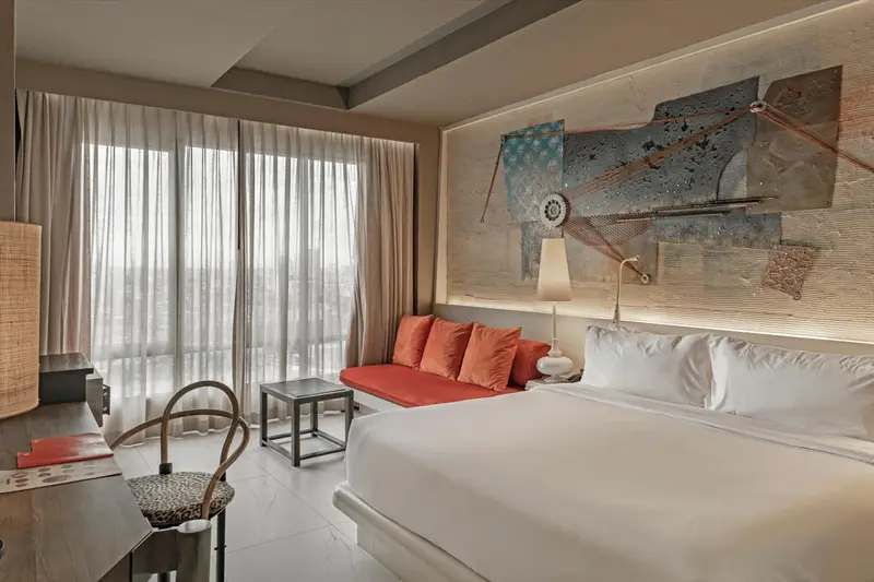 Une chambre lumineuse avec un grand lit et un canapé orange.