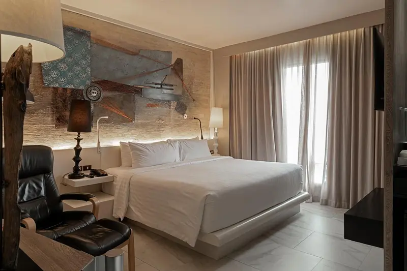 Une chambre lumineuse avec un grand lit et une décoration murale abstraite.