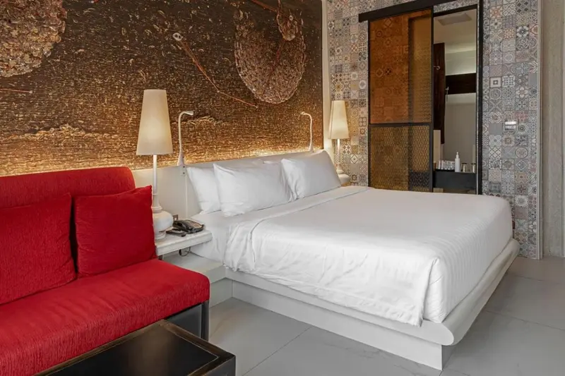 Une chambre lumineuse avec un grand lit et un canapé rouge.