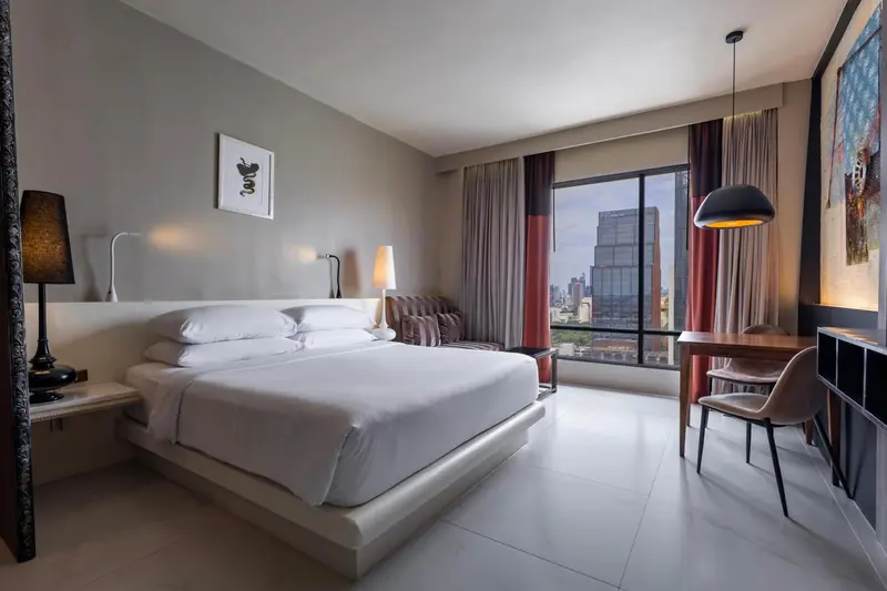 Une chambre lumineuse avec un grand lit et un bureau près de la fenêtre.