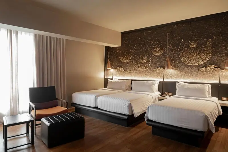 Chambre avec deux lits jumeaux et un fauteuil.