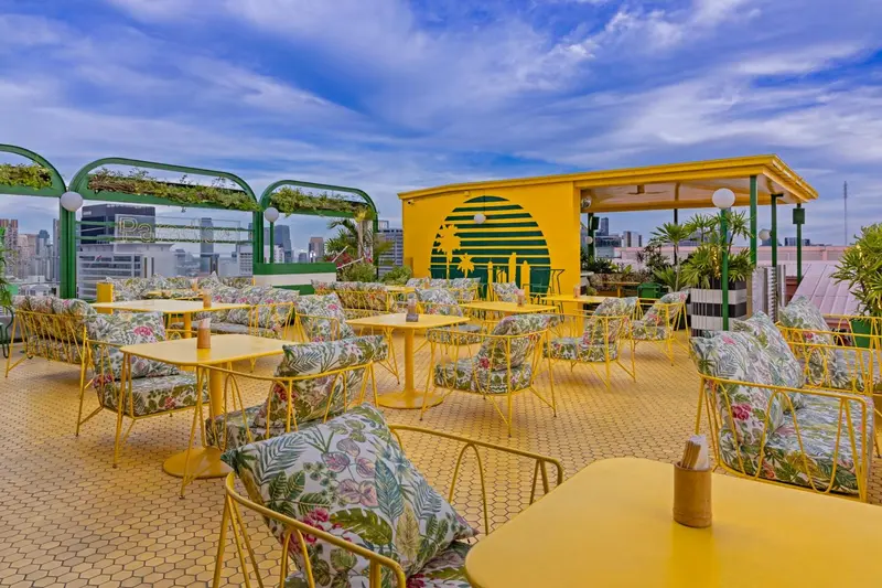 Terrasse jaune avec mobilier fleuri et vue sur la ville.