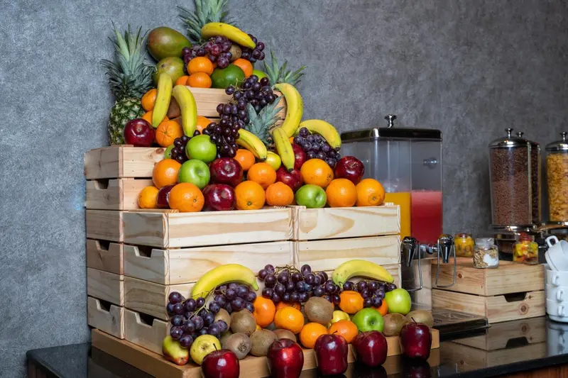 Une pyramide de fruits frais est présentée sur un comptoir en bois.