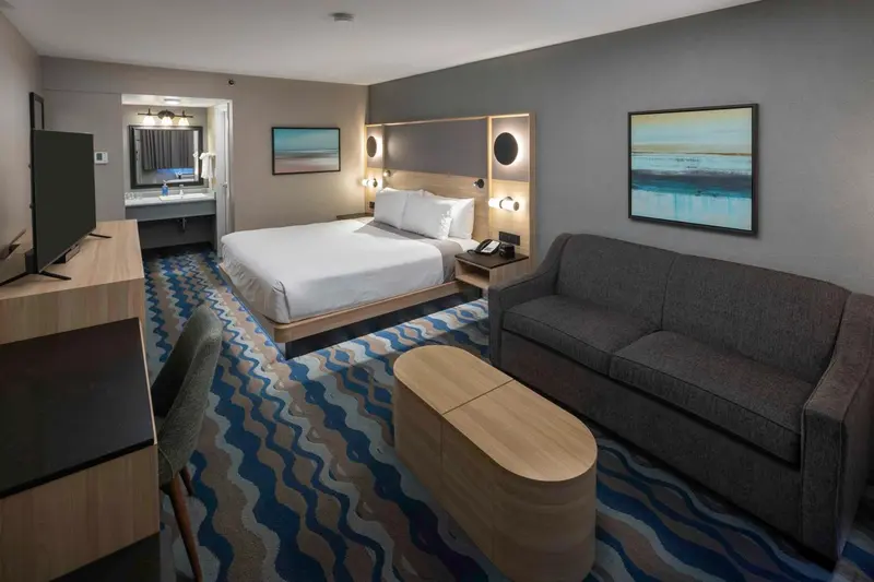 Une chambre d'hôtel lumineuse avec un lit double et un coin salon.