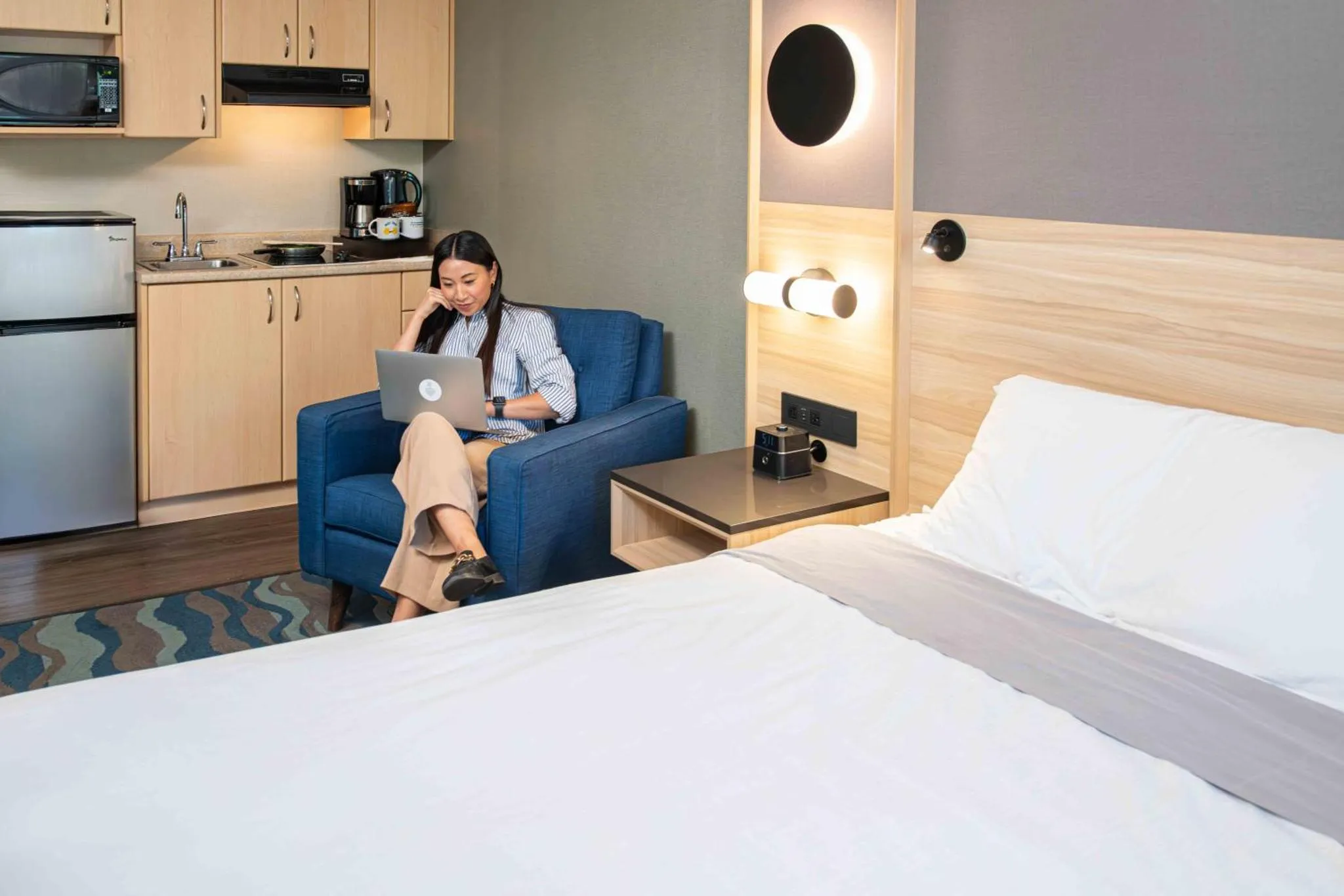 Une femme assise sur un canapé utilise un ordinateur portable dans un espace de vie lumineux.