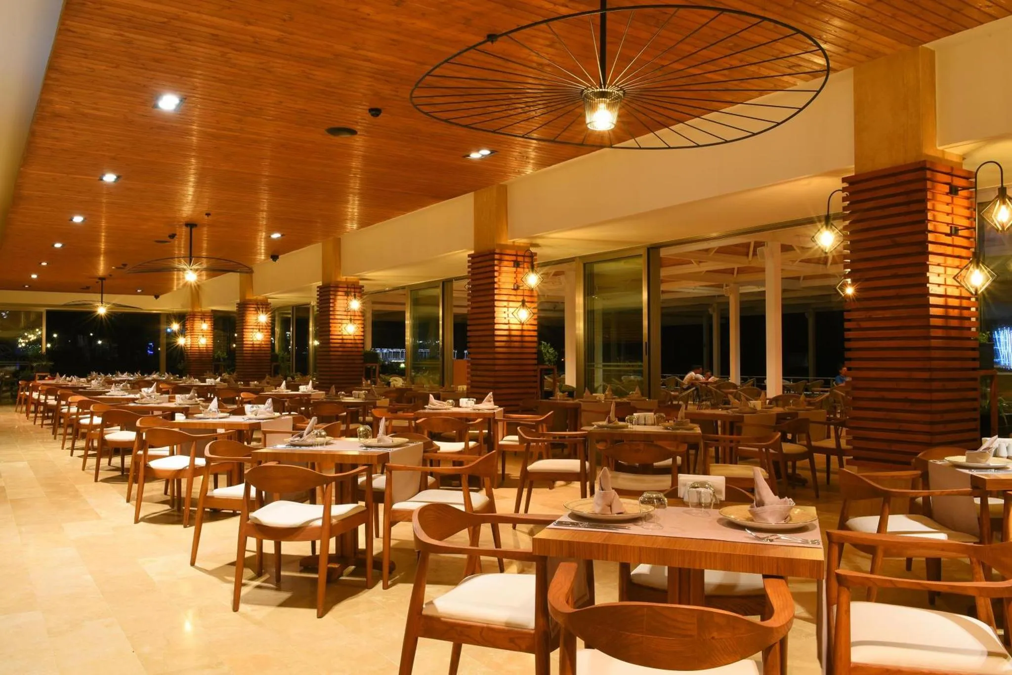 Une salle de restaurant lumineuse avec des tables dressées et un décor en bois.