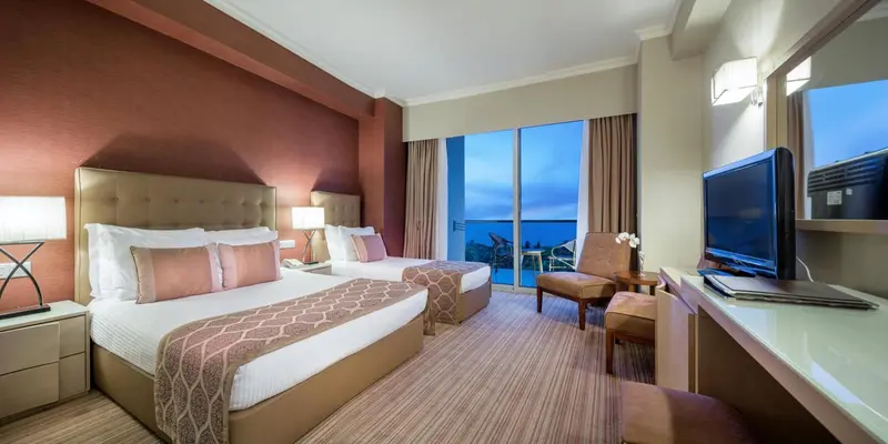 Chambre avec deux lits et vue sur la mer par une baie vitrée.
