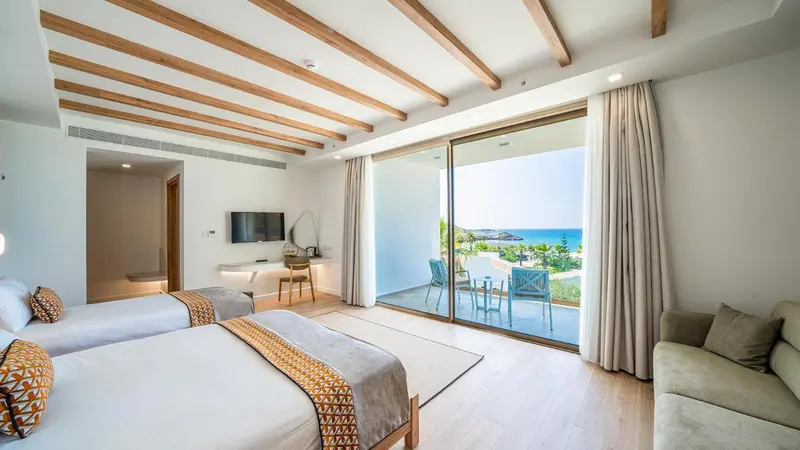 Une chambre lumineuse avec un lit et un canapé donnant sur une vue mer.