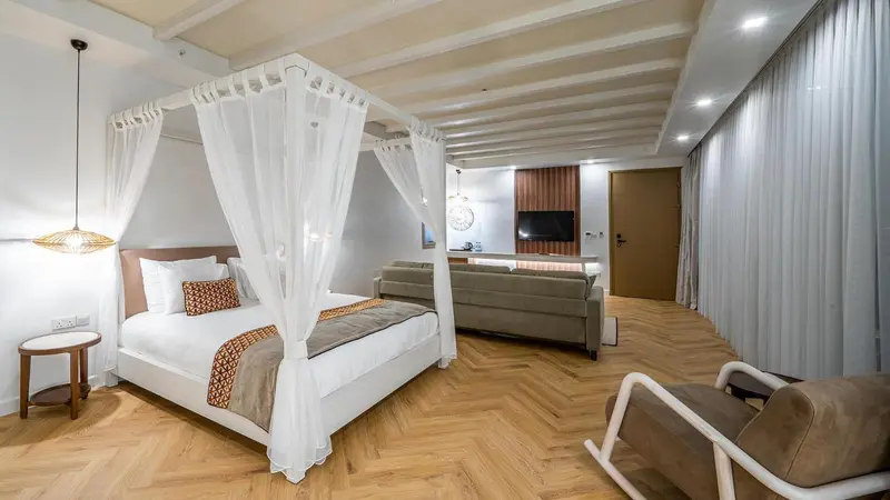 Une chambre spacieuse avec un lit à baldaquin et un coin salon.