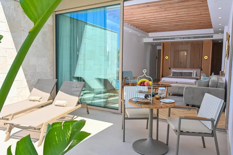 Espace de détente extérieur avec salon et table basse devant une chambre.