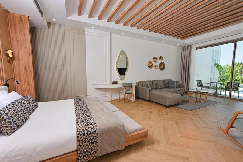 Une chambre lumineuse avec un grand lit et un espace salon.