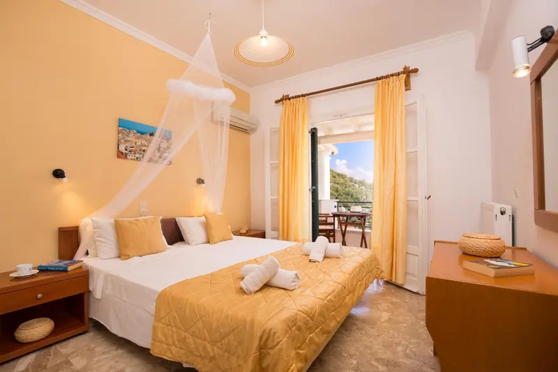 Une chambre lumineuse avec un lit recouvert d'une moustiquaire et une vue sur une terrasse.