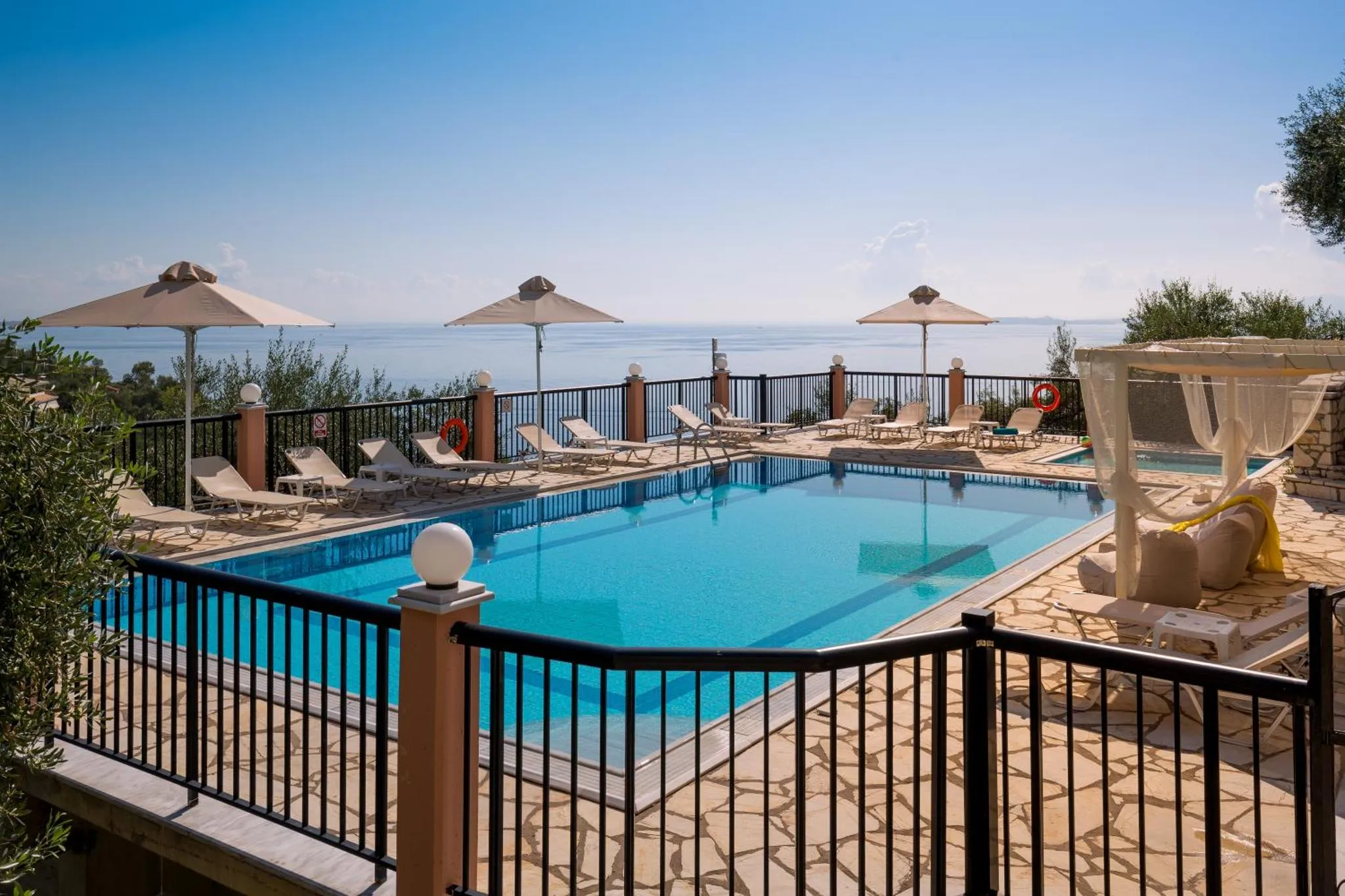 Terrasse avec transats et piscine au bord d'une vue sur la mer.