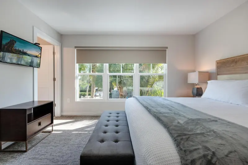 Une chambre lumineuse avec un grand lit et une vue sur la végétation.