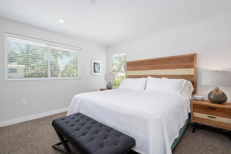Une chambre lumineuse avec un grand lit recouvert d'une courtepointe blanche.