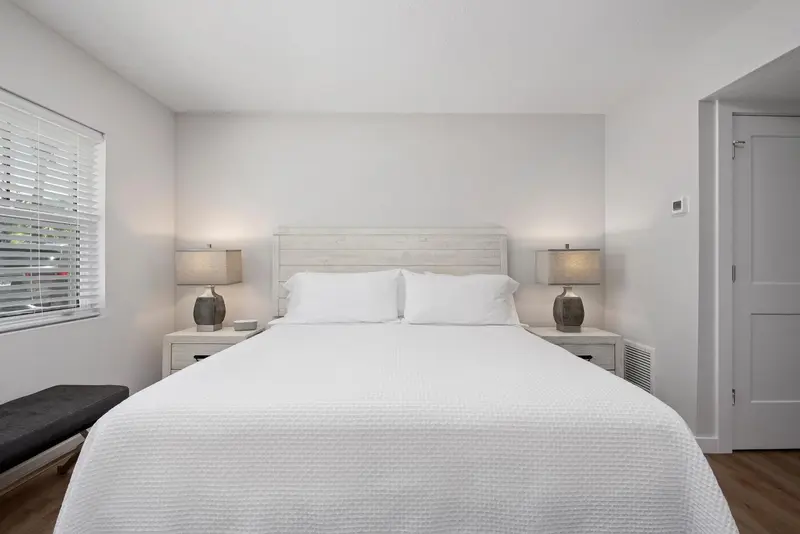 Une chambre lumineuse avec un grand lit recouvert d'une courtepointe blanche.