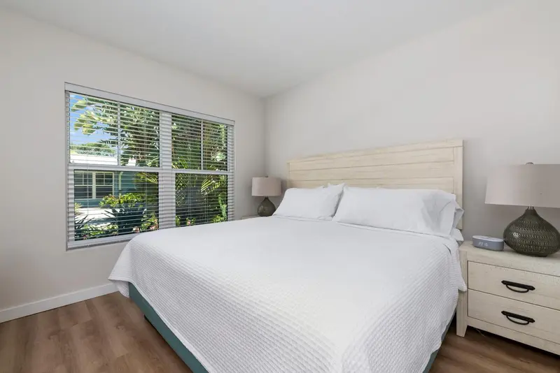 Une chambre lumineuse avec un grand lit recouvert d'une courtepointe blanche.