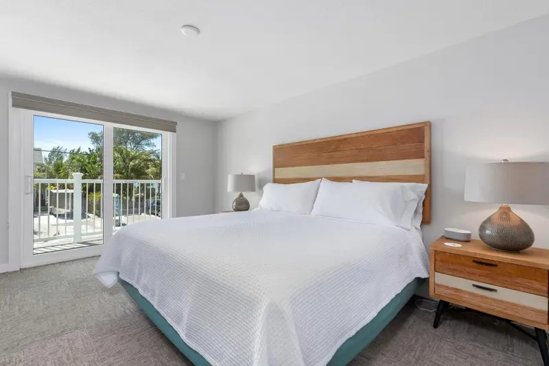 Une chambre lumineuse avec un grand lit et une terrasse accessible par des baies vitrées.