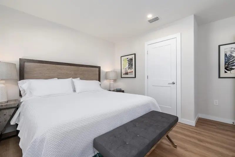 Une chambre lumineuse avec un grand lit recouvert d'une courtepointe blanche.