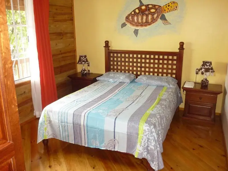 Une chambre lumineuse avec un lit recouvert d'une courtepointe à motifs.