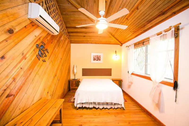 Une chambre lumineuse avec un lit recouvert d'une courtepointe blanche et un plafond en bois.