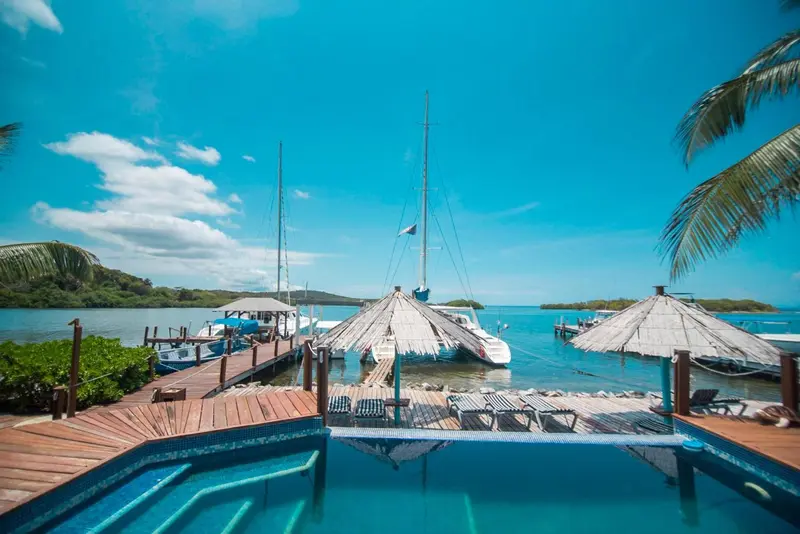 Terrasse en bois avec piscine et vue sur des bateaux amarrés.