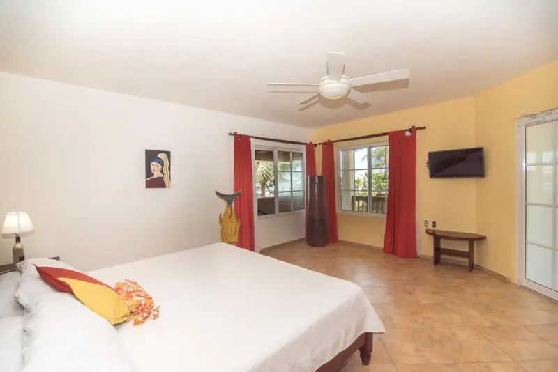 Une chambre lumineuse avec un grand lit et un ventilateur au plafond.