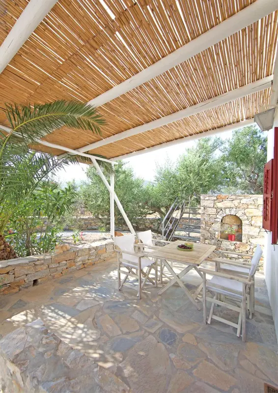 Une table et des chaises sont disposées sur une terrasse pavée ombragée.
